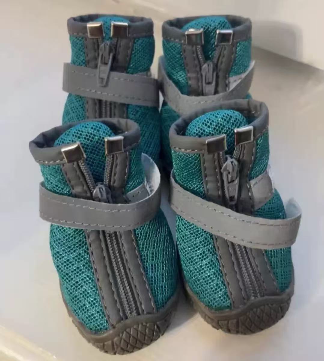 Four teal mesh CozyVale dog boots